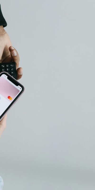Hands using smartphone and terminal for cashless payment, showcasing modern transaction methods.